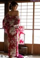 A woman in a red kimono standing in front of a window.