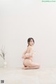 A woman in a white bikini sitting on the floor.