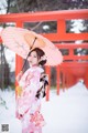 A woman in a kimono holding an umbrella in the snow.