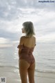 A woman standing on a beach next to the ocean.