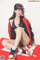 A woman sitting on a red and white rug with a pair of shoes.