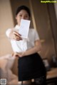 A woman holding up a business card in front of a mirror.